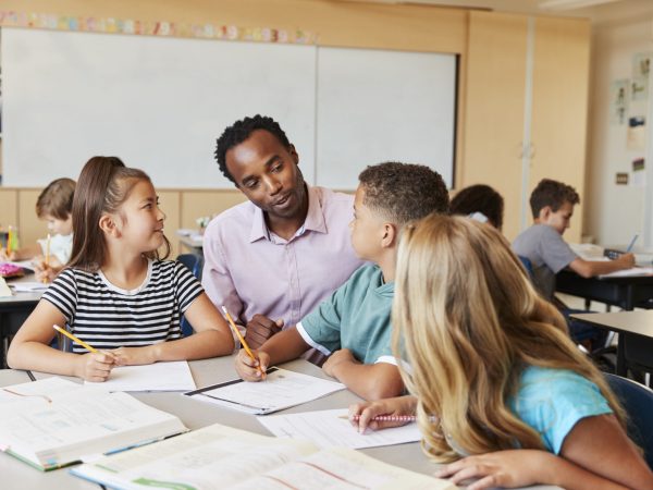 Teacher working with elementary school kids at their desk